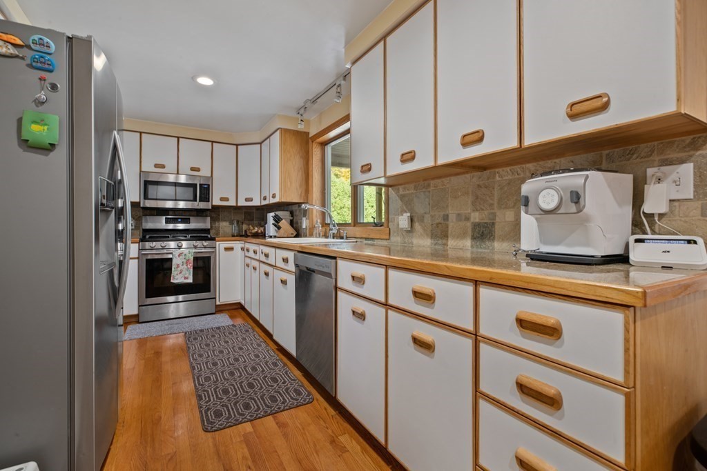 19 Manor Avenue Natick, MA 01760 - Photo 9 of 29 a kitchen with kitchen island granite countertop wooden cabinets and white appliances