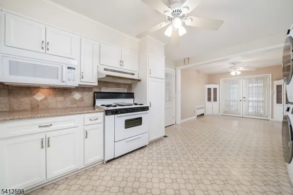 a kitchen with granite countertop white cabinets and white appliances