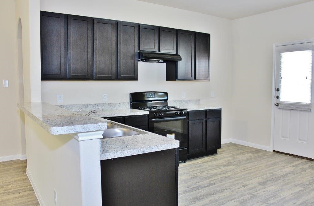 12434 Gemma Lane Houston, TX 77044 - Photo 3 of 15 a kitchen with granite countertop wooden cabinets and black appliances