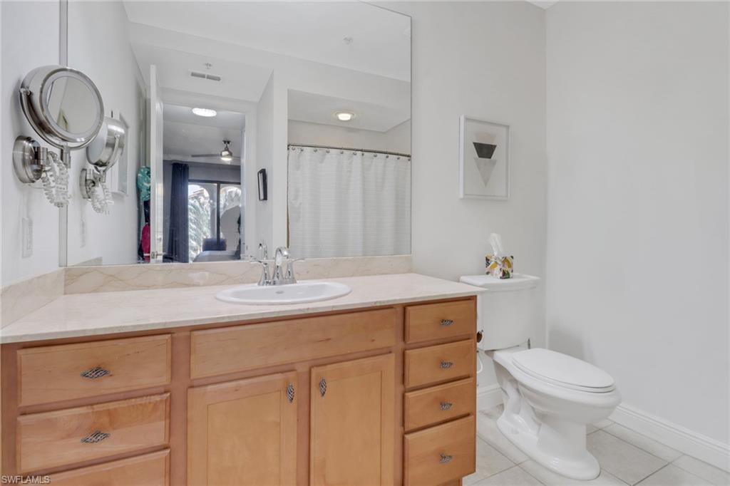 8011 Via Monte Carlo Way, Unit 2208 Estero, FL 33928 - Photo 20 of 34 a bathroom with a granite countertop sink a toilet and a mirror