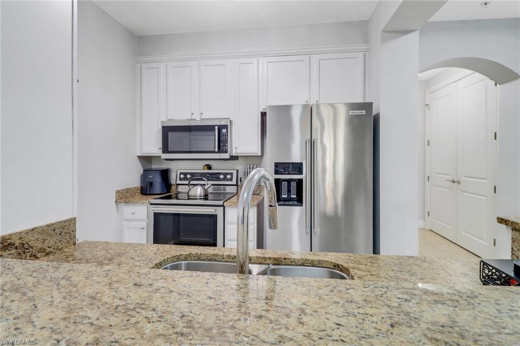 8011 Via Monte Carlo Way, Unit 2208 Estero, FL 33928 - Photo 5 of 34 a kitchen with granite countertop a refrigerator stove and microwave