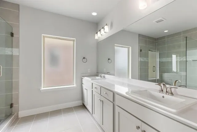 a spacious bathroom with a double vanity sink a mirror and a bathtub