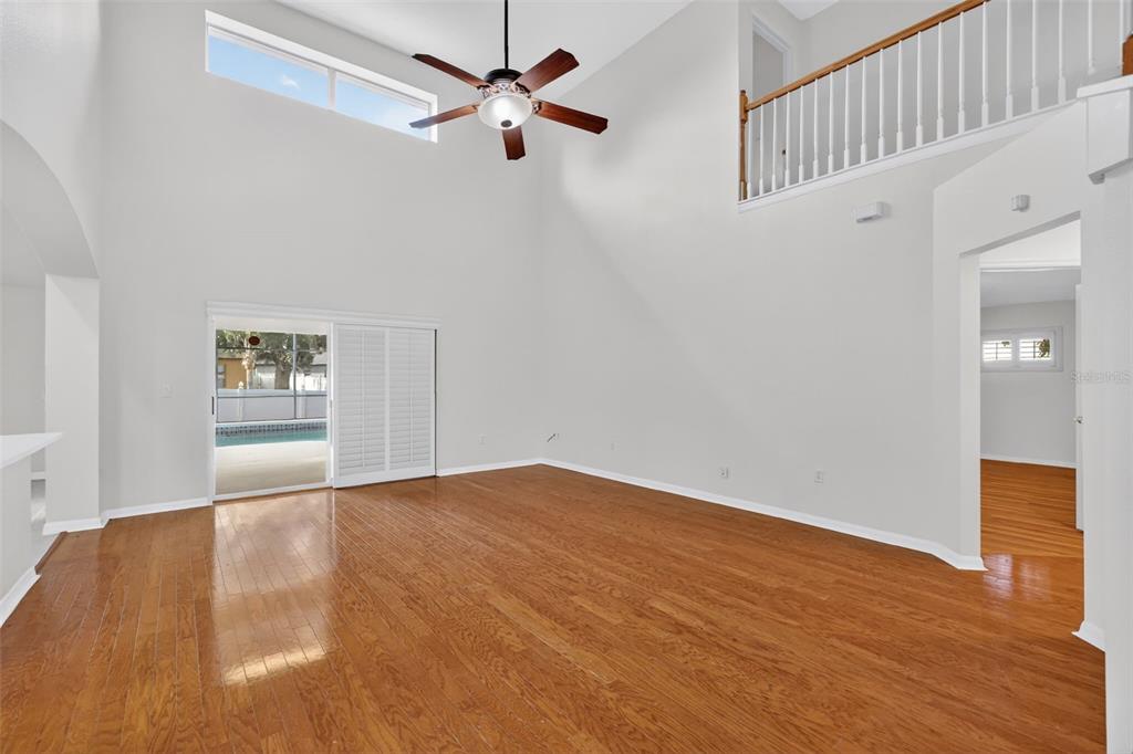 729 Strihal Loop Oakland, FL 34787 - Photo 16 of 49 an empty room with wooden floor chandelier fan and windows