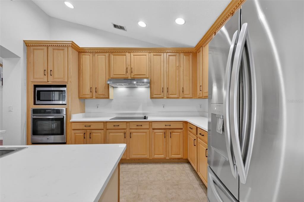 729 Strihal Loop Oakland, FL 34787 - Photo 21 of 49 a kitchen with stainless steel appliances granite countertop a refrigerator a oven and white cabinets with wooden floors