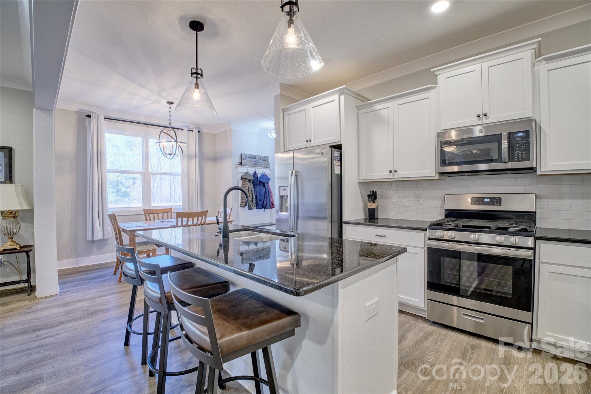 398 Kingsburry Road Clover, SC 29710 - Photo 11 of 48 a kitchen with stainless steel appliances granite countertop a stove a microwave a dining table and chairs with wooden floor