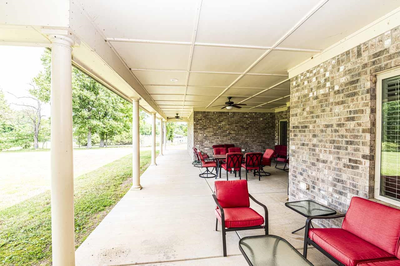 185 Belmont Road Mason, TN 38049 - Photo 9 of 38 Expansive covered patio featuring a concrete surface, column supports, ceiling fans, and a brick exterior wall with a window