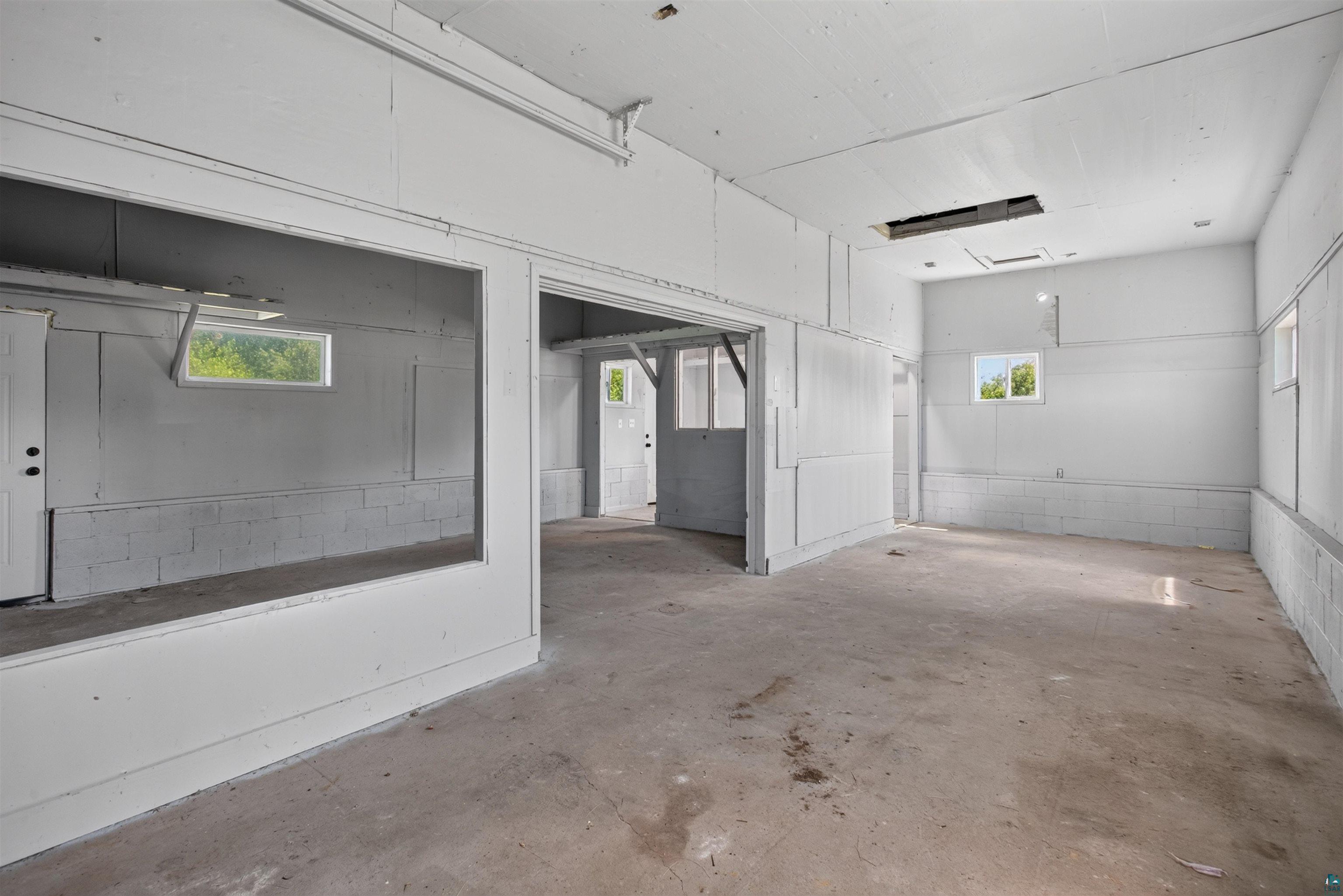 5868 Rice Lake Road Duluth, MN 55803 - Photo 35 of 39 Open, unfinished interior space with concrete flooring, multiple windows, and a partially framed entryway