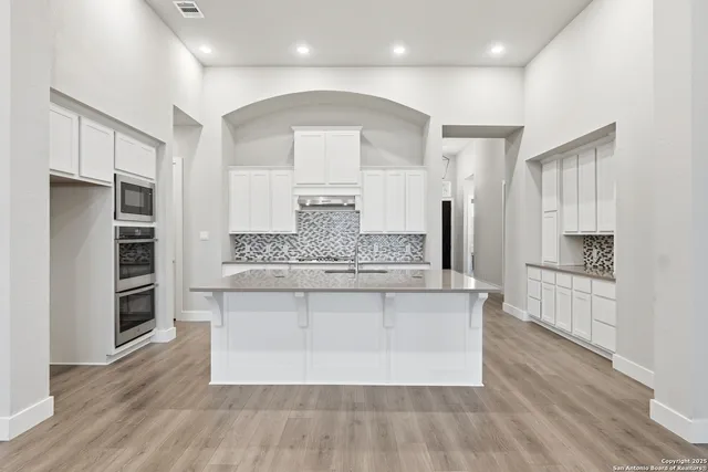 a large kitchen with stainless steel appliances a large counter top and a wooden floors