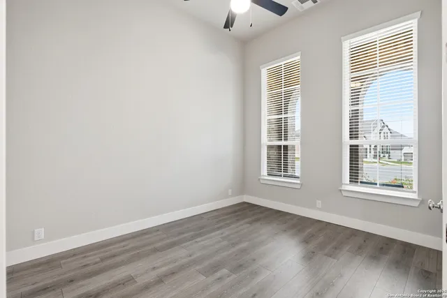 a view of an empty room with wooden floor and a window