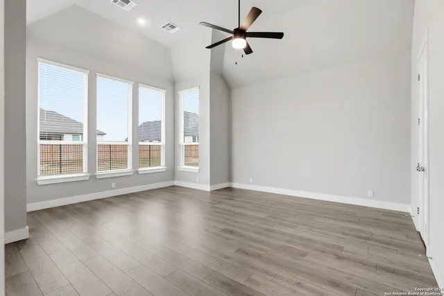 a view of empty room with wooden floor and fan