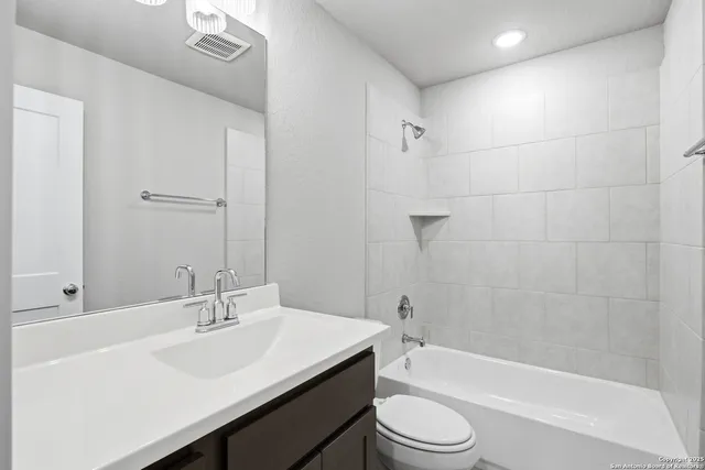 a bathroom with a bathtub shower sink vanity mirror and toilet
