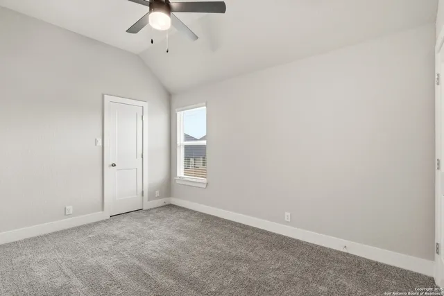 an empty room with a ceiling fan and window