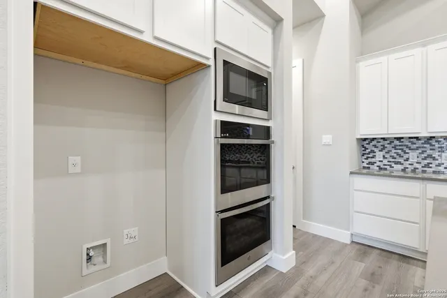 a kitchen with white cabinets and stainless steel appliances