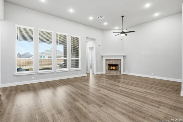 an empty room with wooden floor fireplace and windows
