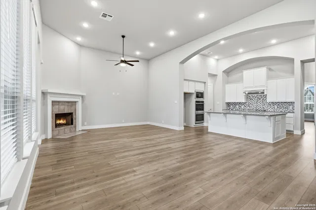 a view of an empty room with a fireplace and kitchen view