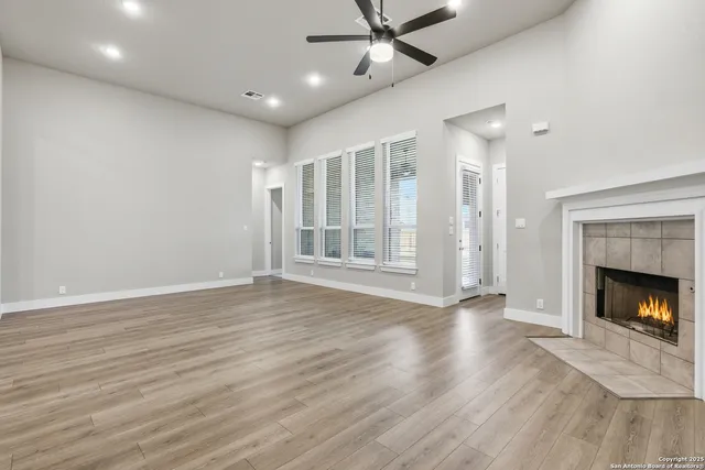 a view of an empty room with wooden floor fireplace and a window