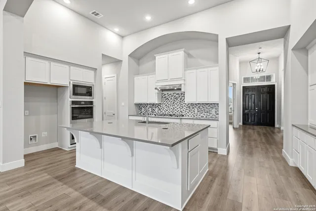 a large kitchen with stainless steel appliances granite countertop a lot of counter space and wooden floor