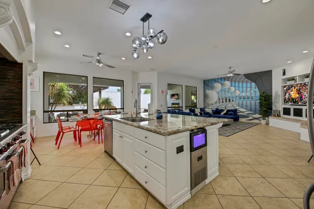 a kitchen with stainless steel appliances kitchen island granite countertop a table chairs sink and cabinets