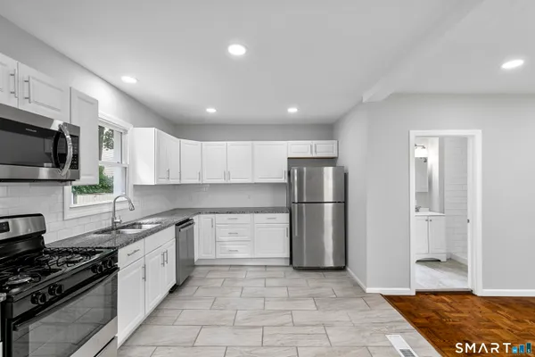 a kitchen with stainless steel appliances granite countertop a refrigerator a stove a sink a microwave and cabinets