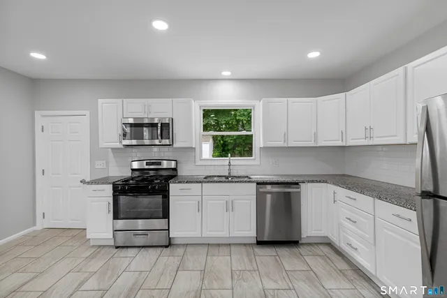 a kitchen with white cabinets appliances and a sink