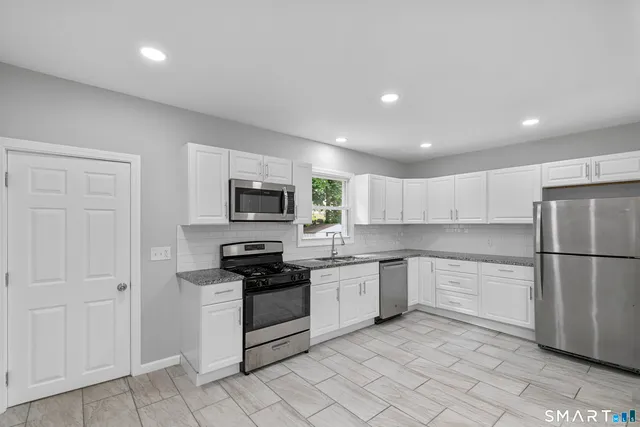 a kitchen with stainless steel appliances granite countertop a refrigerator and a stove top oven