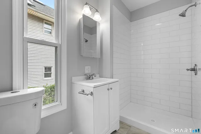 a bathroom with a toilet sink vanity tub and mirror
