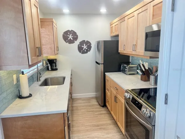 a kitchen with a sink a stove top oven and refrigerator