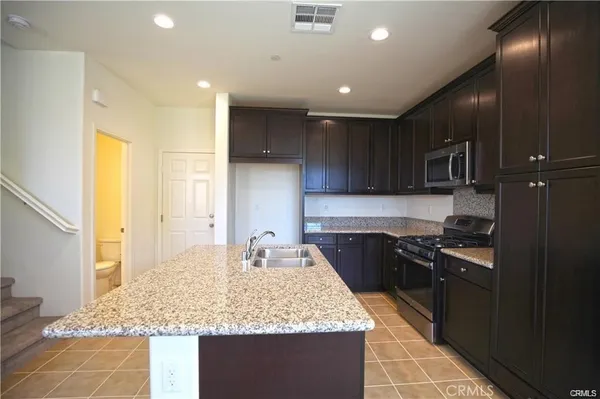 a kitchen with kitchen island granite countertop stainless steel appliances sink stove microwave and cabinets
