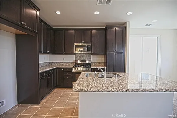 a kitchen with kitchen island granite countertop stainless steel appliances a sink and a refrigerator