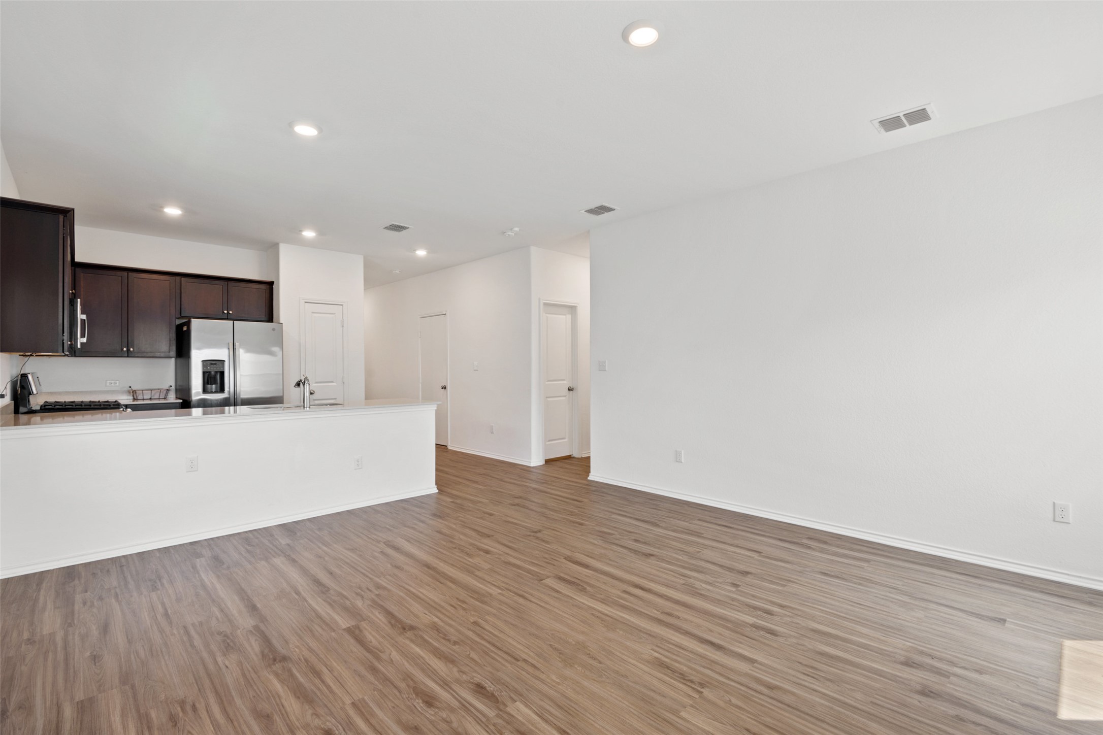 13803 Tordillo Drive Elgin, TX 78621 - Photo 12 of 39 Kitchen with dark brown cabinets, light wood-type flooring, a peninsula, stainless steel appliances, and recessed lighting