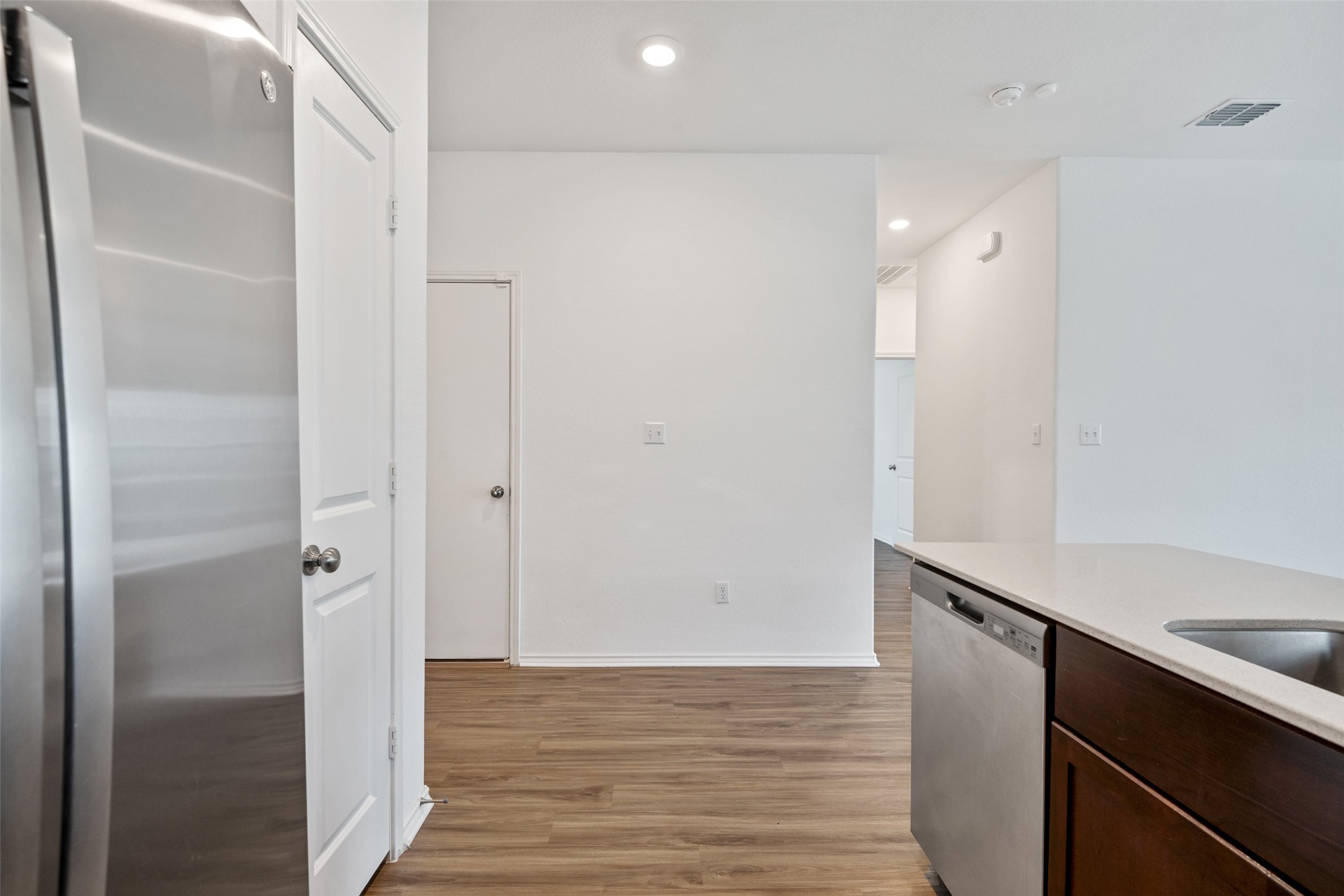 13803 Tordillo Drive Elgin, TX 78621 - Photo 7 of 39 Kitchen featuring stainless steel appliances, dark brown cabinetry, light wood finished floors, recessed lighting, and light stone countertops