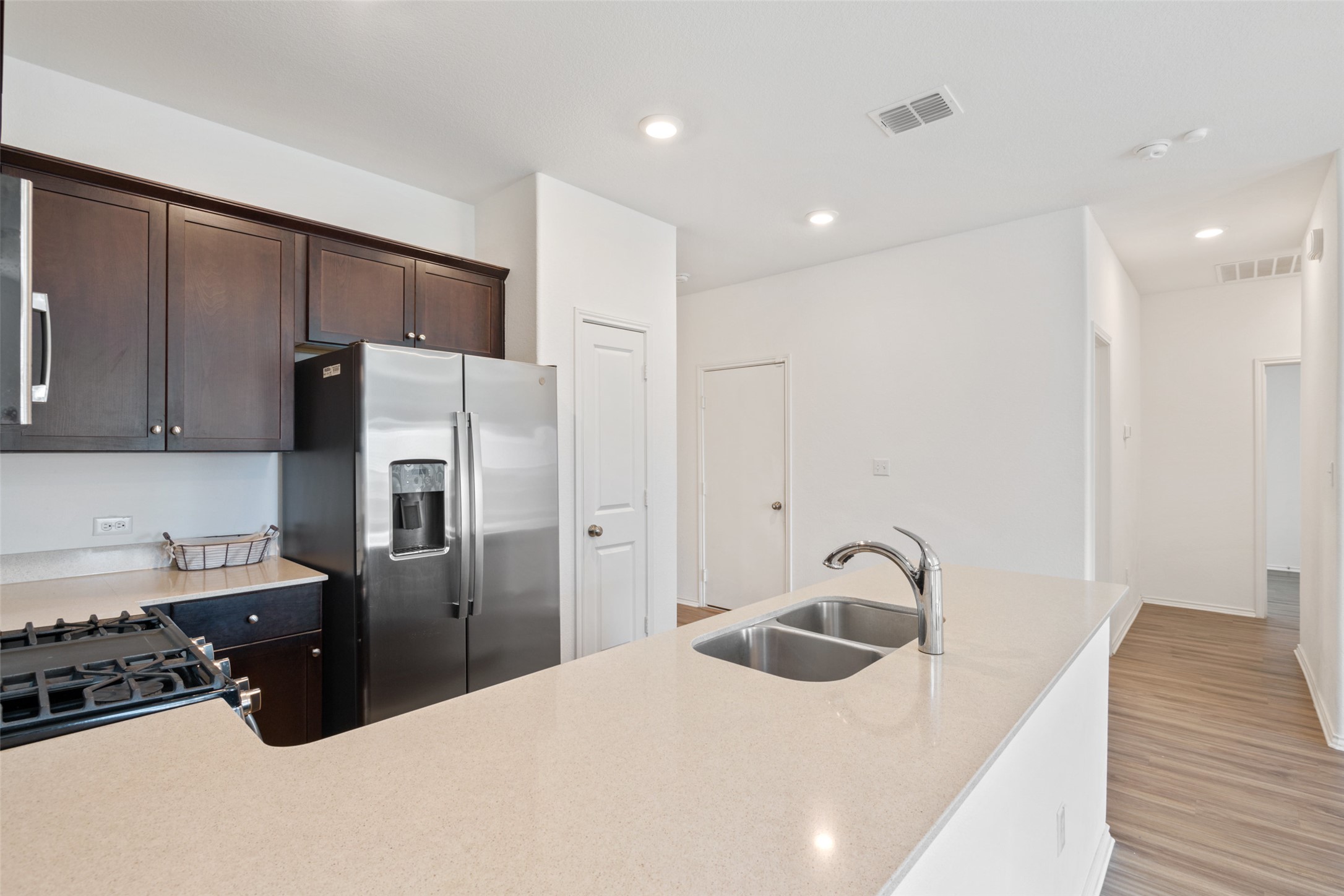 13803 Tordillo Drive Elgin, TX 78621 - Photo 8 of 39 Kitchen featuring stainless steel refrigerator with ice dispenser, light wood-style flooring, recessed lighting, dark brown cabinets, and a peninsula