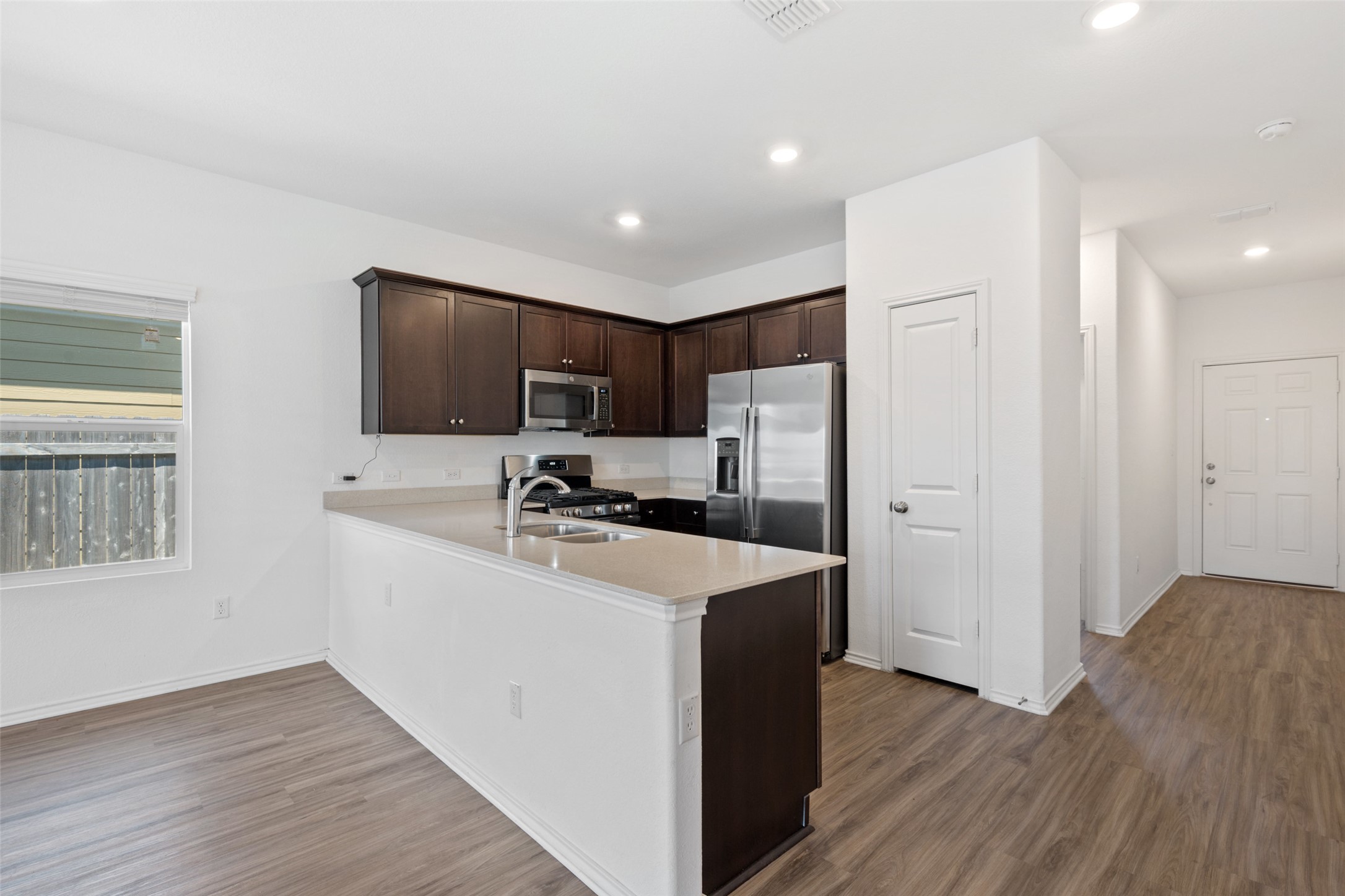 13803 Tordillo Drive Elgin, TX 78621 - Photo 9 of 39 Kitchen with dark brown cabinets, a peninsula, stainless steel appliances, dark wood-type flooring, and recessed lighting