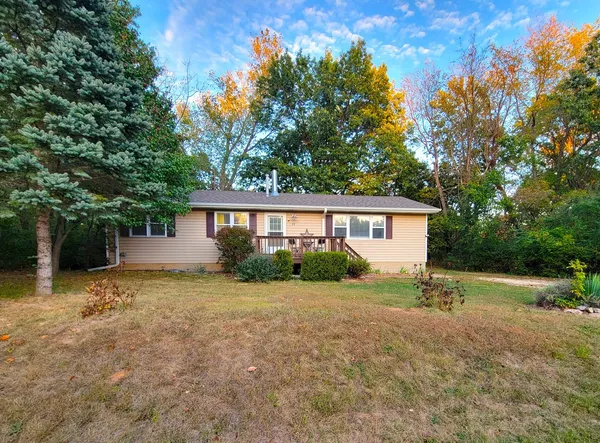 a view of a house with a big yard and large trees