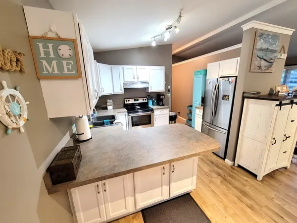 a kitchen with granite countertop a refrigerator a sink a stove and white cabinets