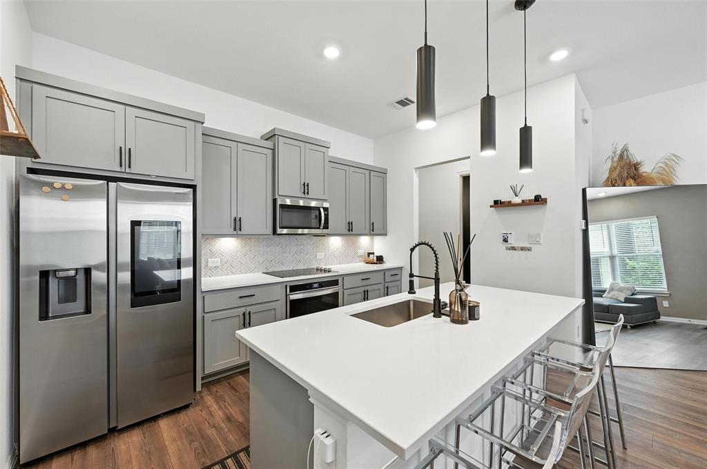 7513 Laburnam Road Dallas, TX 75228 - Photo 7 of 23 a kitchen with stainless steel appliances a refrigerator a stove a sink a dining table and chairs with wooden floor