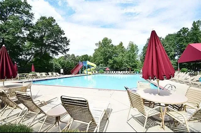 a view of swimming pool with seating space and trees in the background