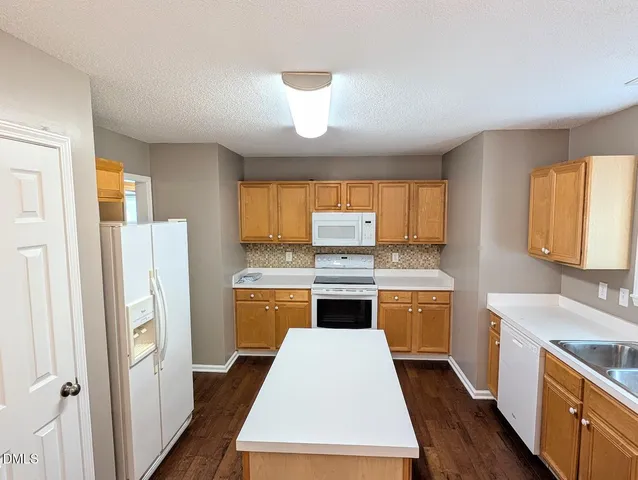 a kitchen with a refrigerator a stove a sink dishwasher and wooden cabinets with wooden floor