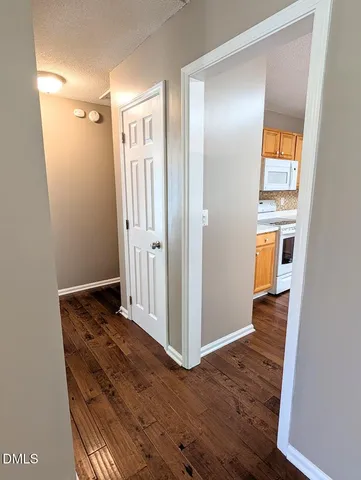 a view of a hallway with wooden floor and closet