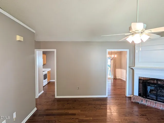 a view of an empty room with wooden floor fireplace and a window