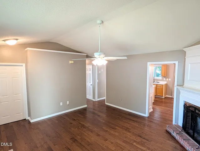 an empty room with wooden floor a fireplace and entryway