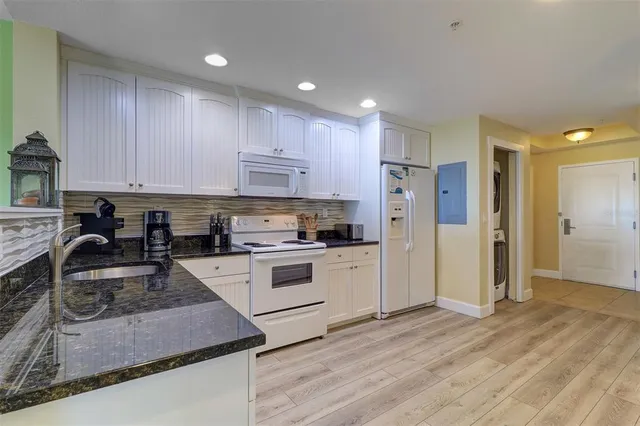 a kitchen with granite countertop white cabinets and white appliances