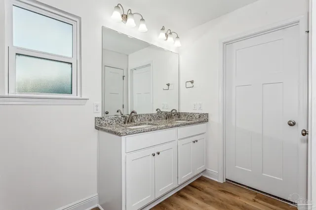 a bathroom with a granite countertop double vanity sink and a mirror