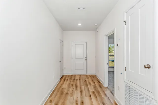 a view of a hallway with wooden floor and a bathroom