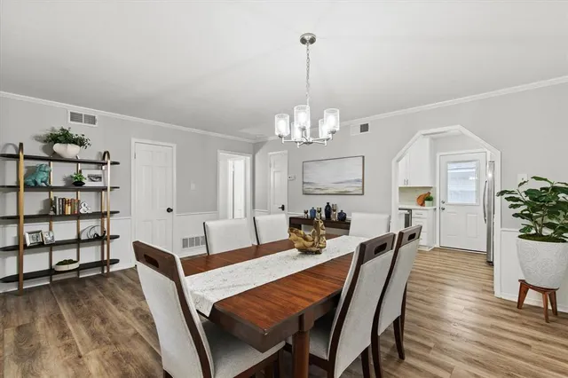 a view of a dining room and livingroom with furniture wooden floor a chandelier