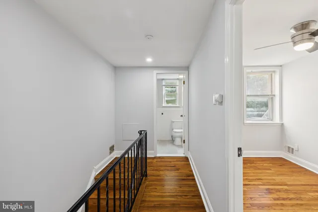 a view of a hallway with wooden floor and a bathroom