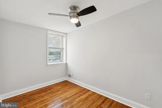 an empty room with wooden floor fan and windows