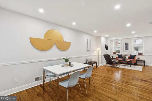 a living room with furniture kitchen view and a wooden floor