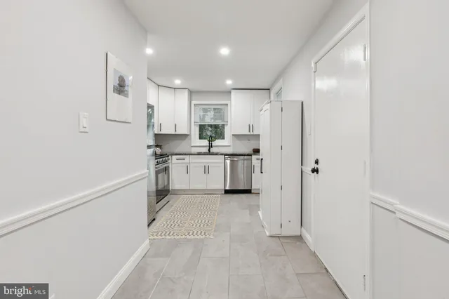 a kitchen with stainless steel appliances granite countertop a refrigerator sink and white cabinets