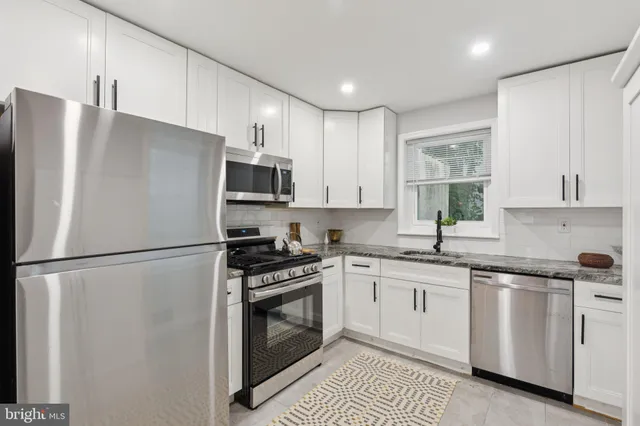 a white kitchen with sink stainless steel appliances and cabinets